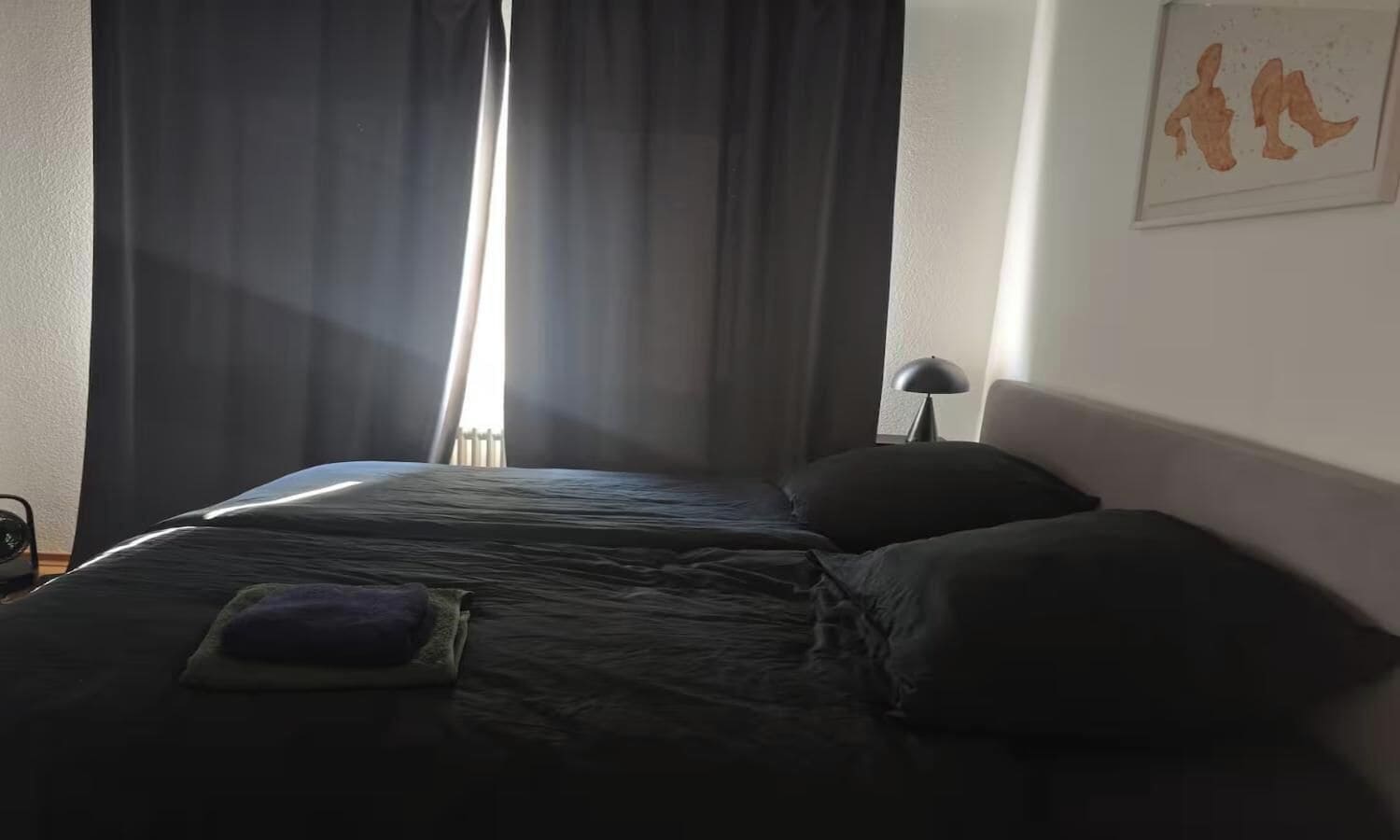 Ein Hotelzimmer mit einem Bett, einem Nachttisch, einer Lampe und einem Gemälde an der Wand.
