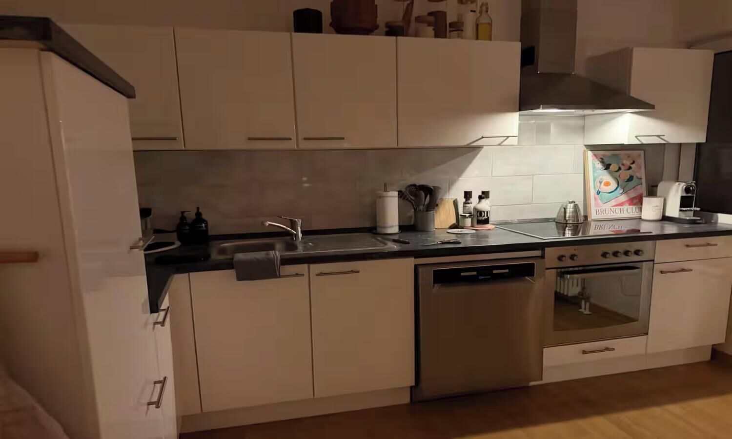Eine Küche mit weißen Schränken, einem Edelstahl-Geschirrspüler, einem Backofen und einem Spülbecken mit Armatur.