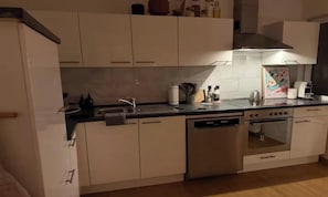 Eine Küche mit weißen Schränken, einem Edelstahl-Geschirrspüler, einem Backofen und einem Spülbecken mit Armatur.