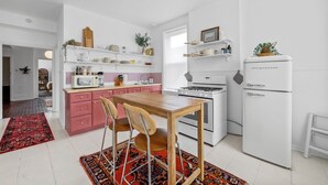 A modern kitchen with pink cabinets, a wooden table, and a white refrigerator. - NEW! Best Value, Spacious, 1BD, Near Barnes, Nurse Approved! (St. Louis)