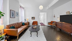 A modern living room with a sofa, armchairs, a coffee table, and a TV stand. - NEW! Best Value, Spacious, 1BD, Near Barnes, Nurse Approved! (St. Louis)