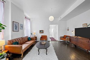 Ein modernes Wohnzimmer mit einer Couch, Sesseln, einem Couchtisch und einem Fernsehschrank.
