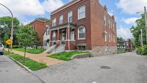 A two-story brick building with a front porch and a driveway. - NEW! Best Value, Spacious, 1BD, Near Barnes, Nurse Approved! (St. Louis)