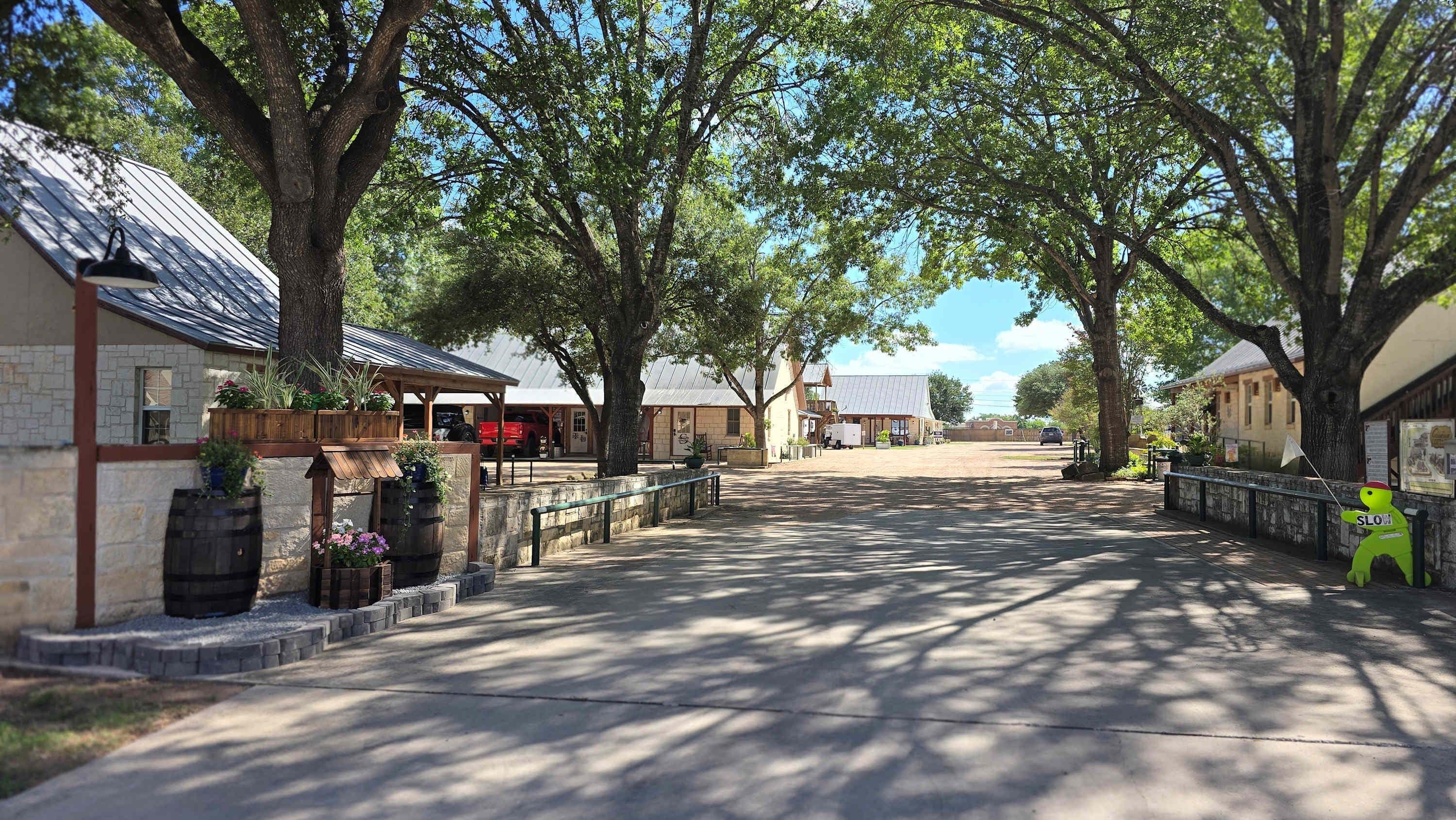 Une rue bordée d’arbres, avec des immeubles, une clôture en bois et une figurine de dinosaure verte.