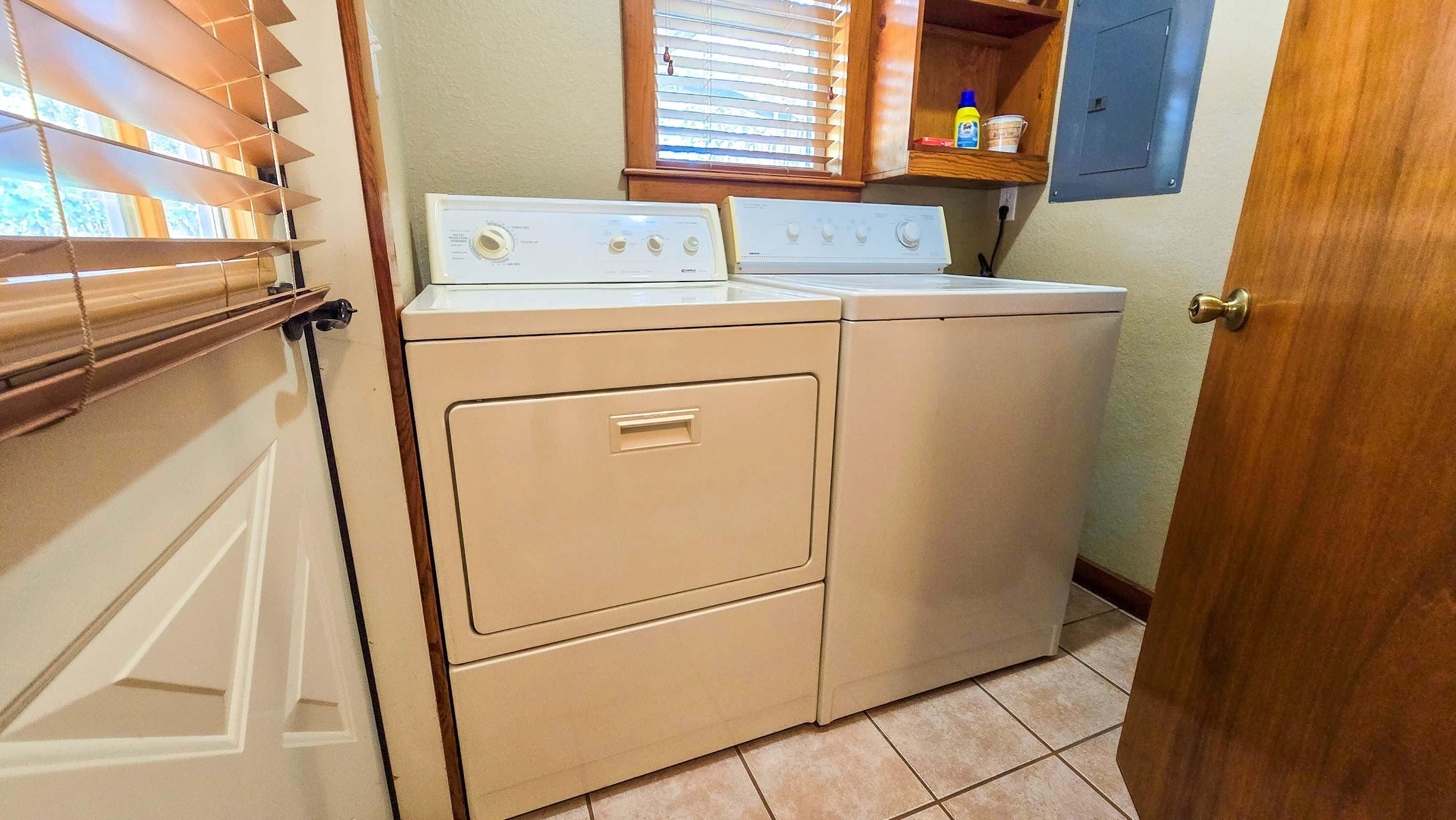 A laundry room with two stacked washers and dryers, a wooden cabinet above, and a door to the right.