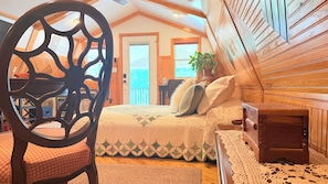 A cozy bedroom with a large bed, a wooden chair, and a small table.