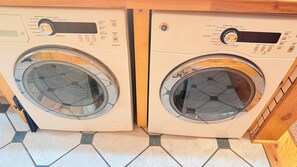 Two front-loading washing machines with control panels, placed side by side on a tiled floor.