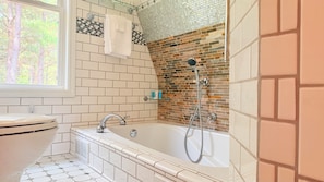 A bathroom with a bathtub, a toilet, and a window.