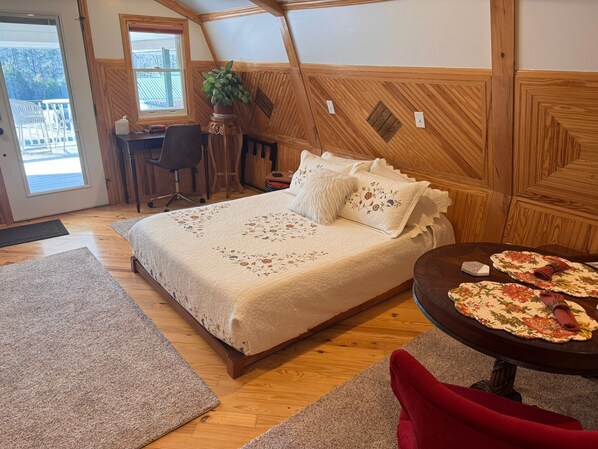 A cozy bedroom with a bed, a desk, and a dining table with placemats.