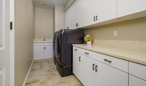 A compact kitchen with white cabinets, a black refrigerator, and a small countertop with a potted plant. - Spacious house with amazing view (West Covina)