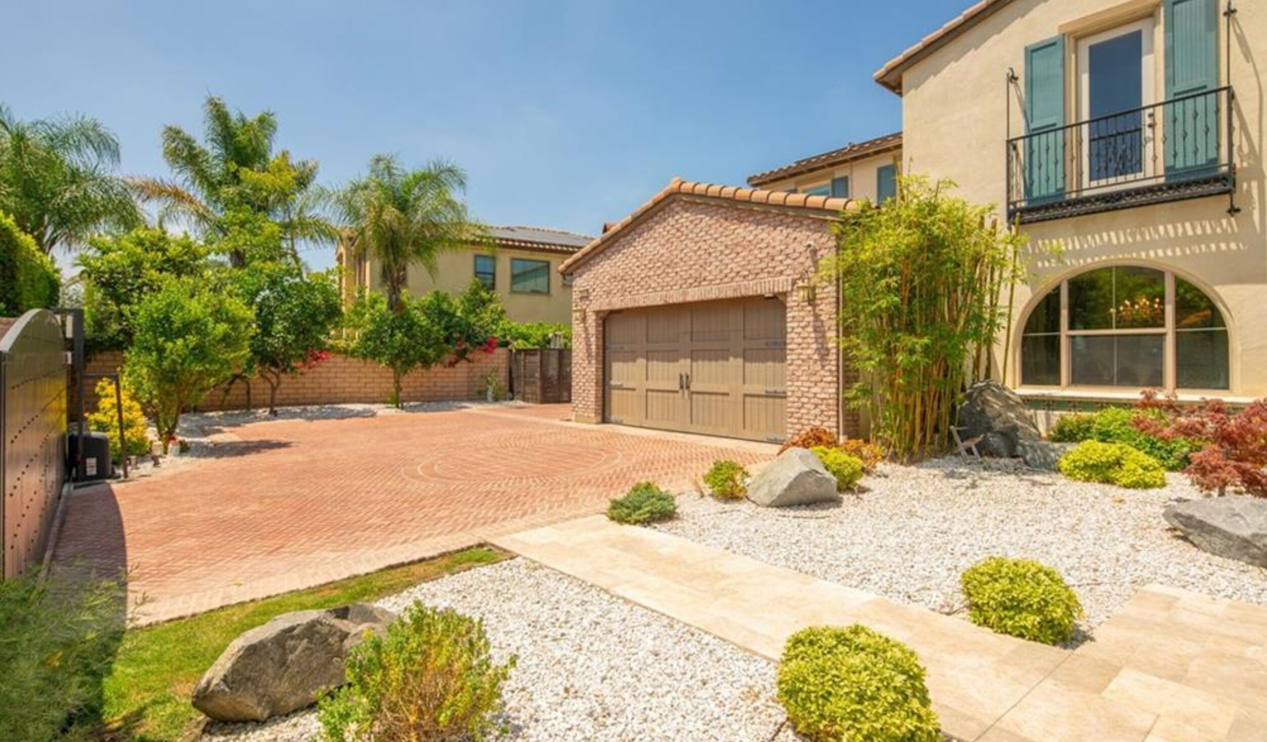 Ein Wohnhaus mit befestigter Auffahrt, Garage und einem angelegten Garten mit verschiedenen Pflanzen und Steinen.