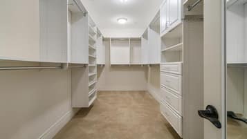 Ein begehbarer Kleiderschrank mit offenen Regalen, Schubladen und einer Tür mit schwarzem Griff.