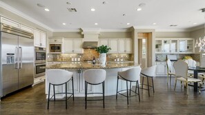 Une cuisine moderne dotée d’un îlot central, d’appareils électroménagers en acier inoxydable et de tabourets de bar.