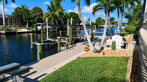 A marina with docked boats, a wooden walkway, and palm trees. - Almare – Gulf Access, Pool, Spa & Boat Dock (Cape Coral)