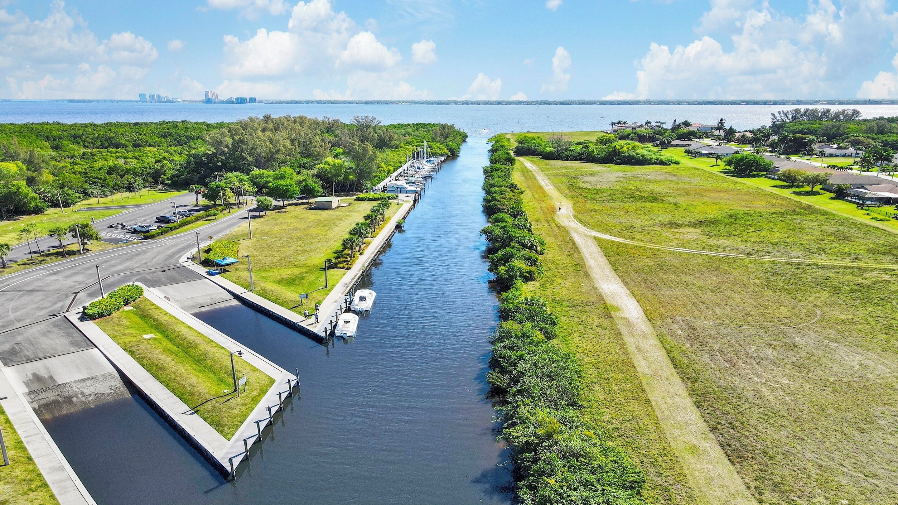 A canal with boats, a road, and greenery.