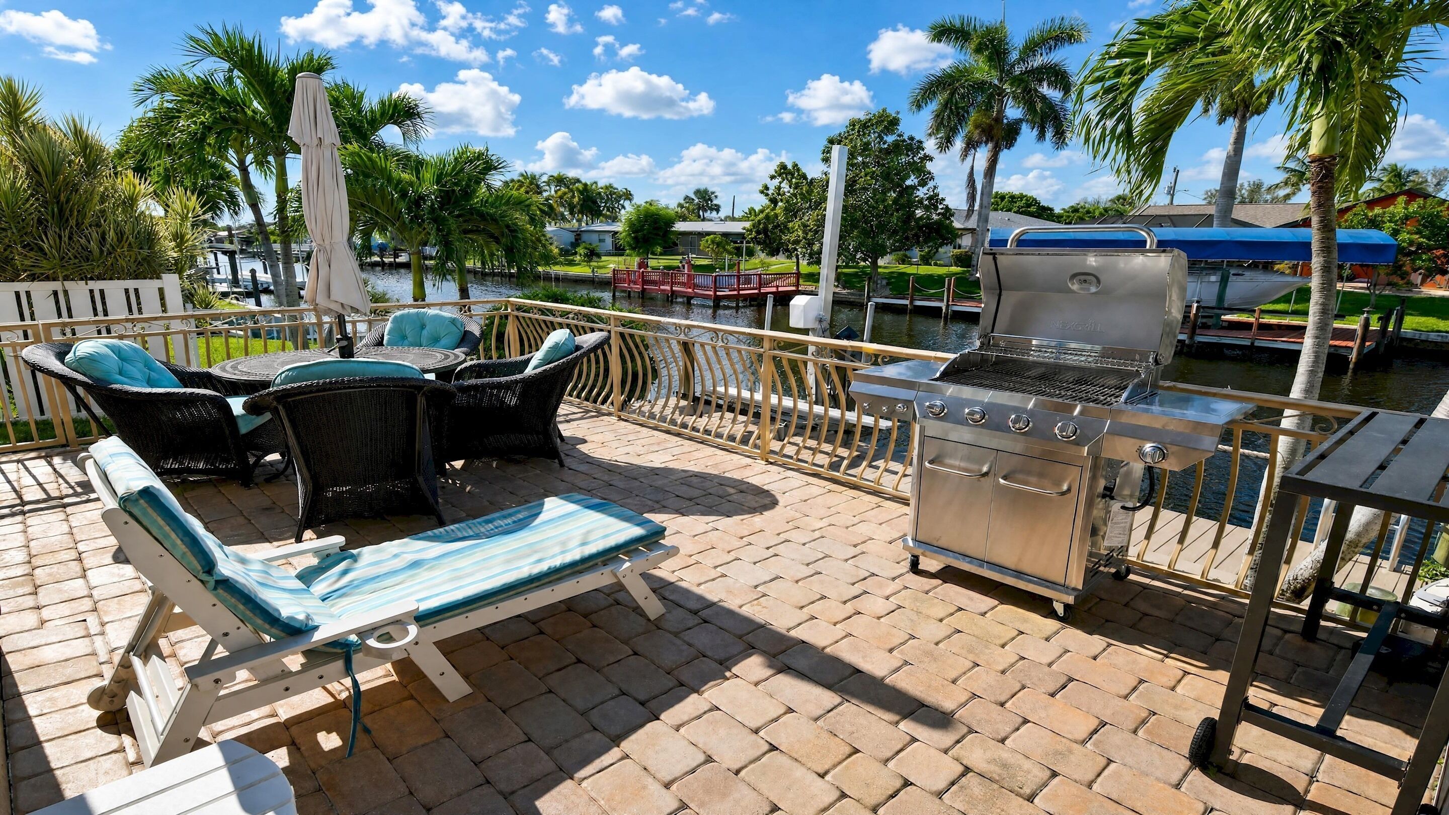 An outdoor patio with a grill, lounge chairs, and a view of a water body.