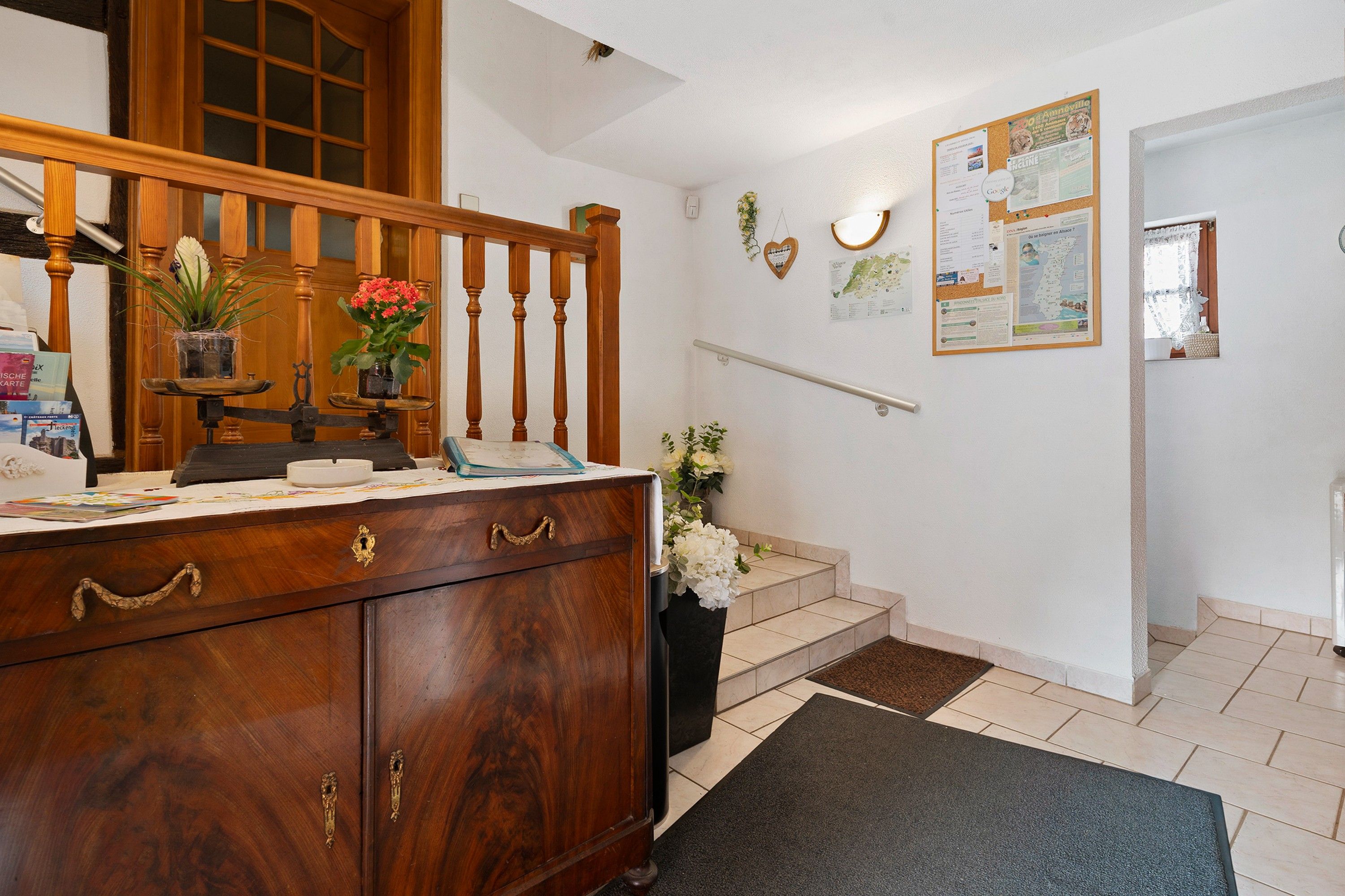 Eine Holztreppe mit Geländer, ein Holzkasten mit Schubladen und ein kleiner Tisch mit einem Blumenstrauß.