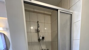 Une salle de bain moderne avec une douche à parois de verre, un lavabo doté d’un distributeur de savon et un miroir.