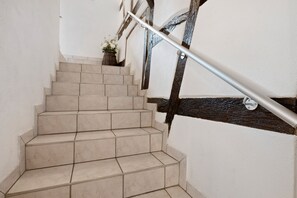 A staircase with beige tiles, a metal handrail, and a dark wooden handrail.