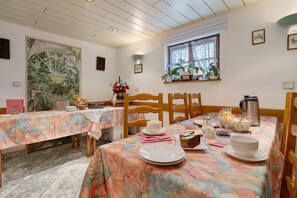 Un comedor con dos mesas, sillas y un ventanal con cortinas de encaje.