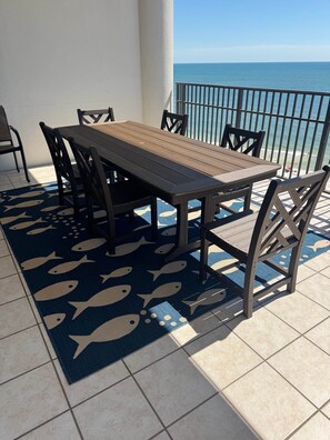 Mesa e cadeiras de madeira numa varanda com vista para o mar.