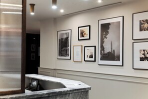 Ein Empfangsbereich mit Marmor-Theke und gerahmten Kunstwerken an der Wand.