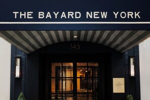 The entrance to The Bayard Hotel in New York, featuring a dark facade, a large arched entrance, and a sign displaying the hotel's name and location. - Bayard | One-Bedroom King | Turtle Bay | Free Breakfast (New York)