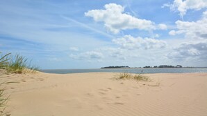 A sandy beach with a clear sky and distant land. - 1 Bed in Wells-next-the-Sea (oc-591) (Wells-next-the-Sea)