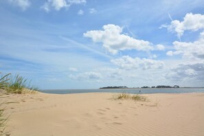 A sandy beach with a clear sky and distant land. - 1 Bed in Wells-next-the-Sea (oc-591) (Wells-next-the-Sea)