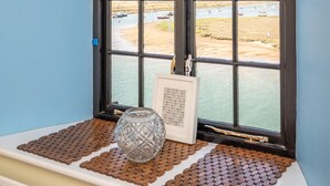 A bay window with a view of a water body and boats, a decorative glass vase, and a framed picture on a textured mat. - 1 Bed in Wells-next-the-Sea (oc-591) (Wells-next-the-Sea)