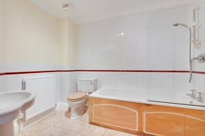 Une salle de bain comprenant des toilettes, un lavabo, une baignoire et une douche.