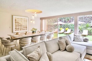 Um interior moderno com área de jantar, sofá e vista para o jardim.