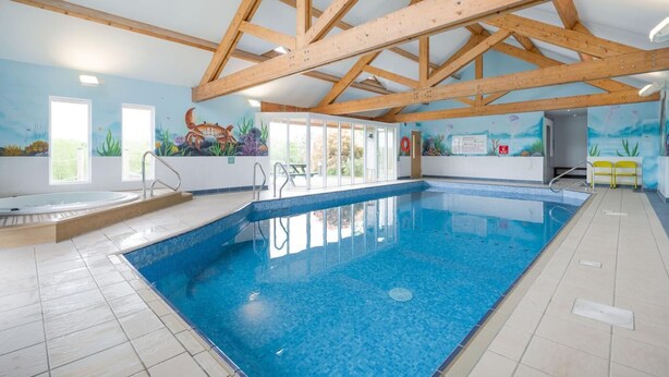 An indoor swimming pool with a tiled floor, wooden beams, and a mural of underwater scenery. - 3 Bed in Kilkhampton (oc-l27383) (Kilkhampton)