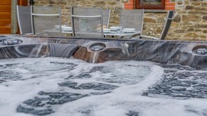 A hot tub with visible jets and a stone wall in the background. - 3 Bed in Kilkhampton (oc-l27383) (Kilkhampton)