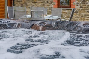 A hot tub with visible jets and a stone wall in the background. - 3 Bed in Kilkhampton (oc-l27383) (Kilkhampton)