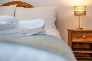 A neatly made bed with white linens, a wooden headboard, and a bedside table with a lamp. - 3 Bed in Kilkhampton (oc-l27383) (Kilkhampton)