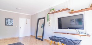 Ein modernes Wohnzimmer mit einem großen Flachbildfernseher an der Wand, einer Bank und einer Tür.