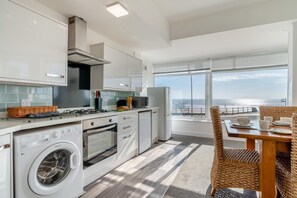 Eine moderne Küche mit integriertem Waschmaschine, ein Essbereich mit Meerblick und ein großes Fenster.