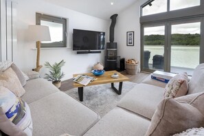 Ein modernes Wohnzimmer mit einer Couch, einem Couchtisch, einem Fernseher und einem Kamin.