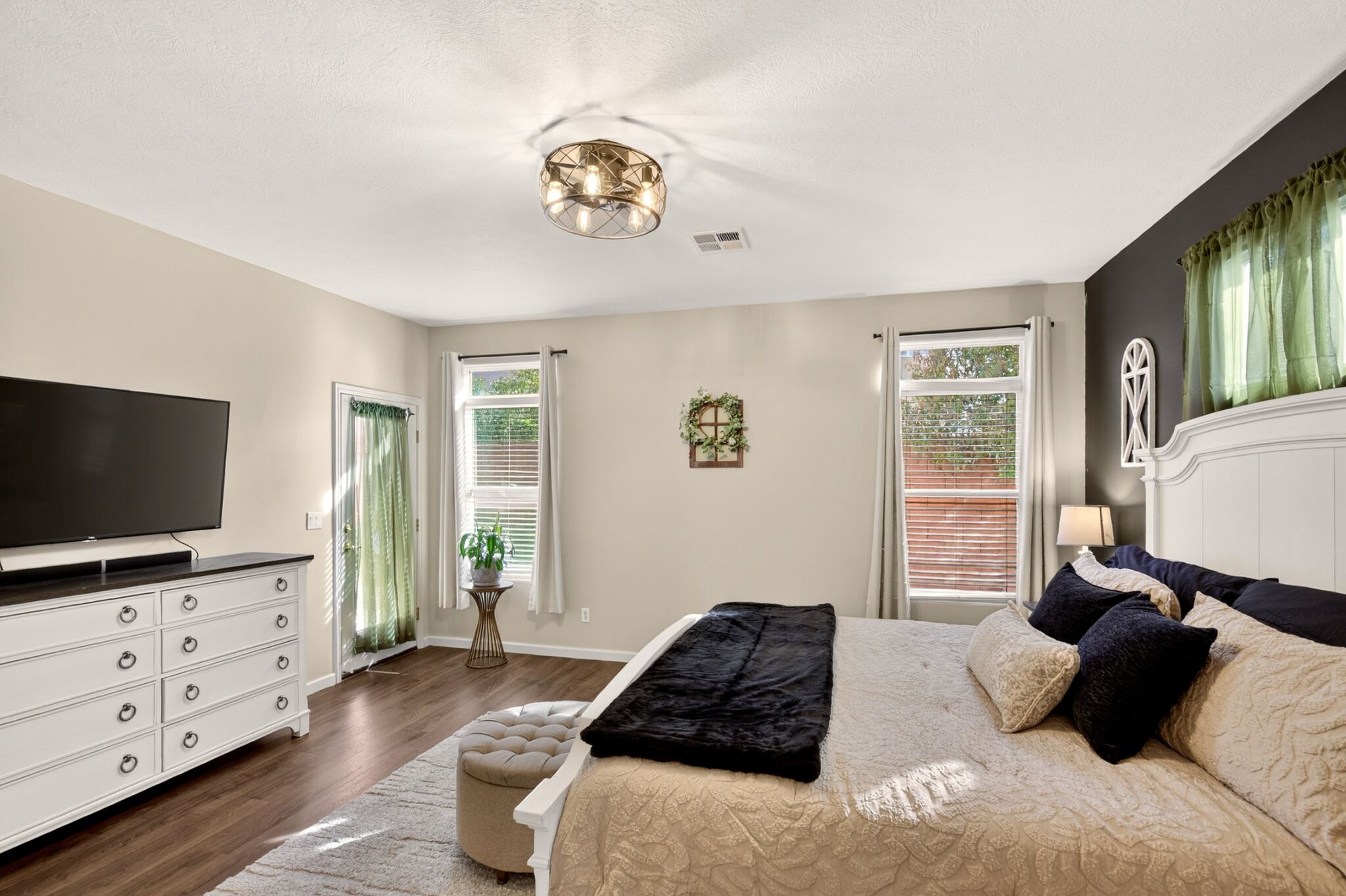 A bedroom with a bed, dresser, television, and a ceiling light fixture.