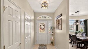 A hallway with white doors, a decorative glass door, a rug, a dining area with a table and chairs, and a ceiling light fixture. - Comfort & Convenience close to Zion, Sand Hollow, Quail Creek & Gooseberry Mesa! (Hurricane)