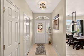 A hallway with white doors, a decorative glass door, a rug, a dining area with a table and chairs, and a ceiling light fixture. - Comfort & Convenience close to Zion, Sand Hollow, Quail Creek & Gooseberry Mesa! (Hurricane)