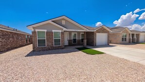 A residential building with a brick facade, a garage, and a well-maintained driveway.