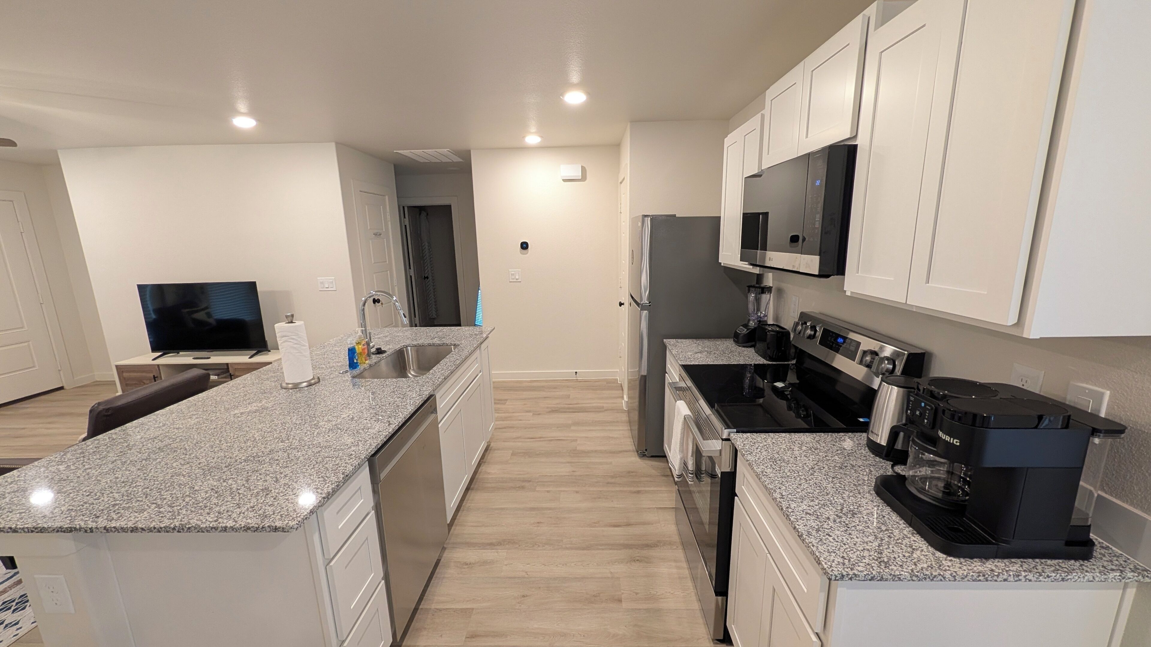 A modern kitchen with granite countertops, stainless steel appliances, and white cabinetry.