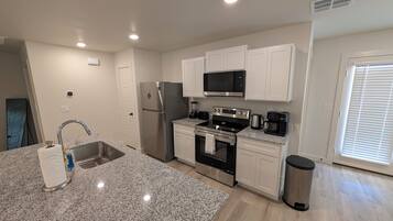 A modern kitchen with granite countertops, stainless steel appliances, and white cabinetry.