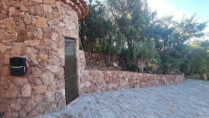 Un edificio de piedra con una reja de metal, un muro de piedra y una zona pavimentada.