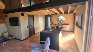 Una cocina moderna con una isla central, un comedor con una silla y vistas al exterior.