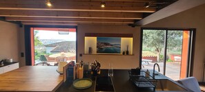 A modern interior with a dining area, a kitchen counter, and a large window offering a view of the outdoors. - Chic House with a Pool in Cannes (Cannes)