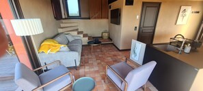 A compact living space with a sofa, chairs, a small table, a kitchen area with a sink, and a staircase leading to an upper level. - Chic House with a Pool in Cannes (Cannes)