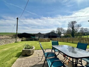 Un patio con una mesa y sillas, un muro de piedra y un césped.